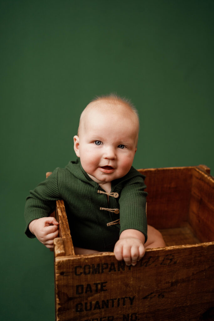 6 month old boy sitting in a wooden crate in Rio, WI Studio