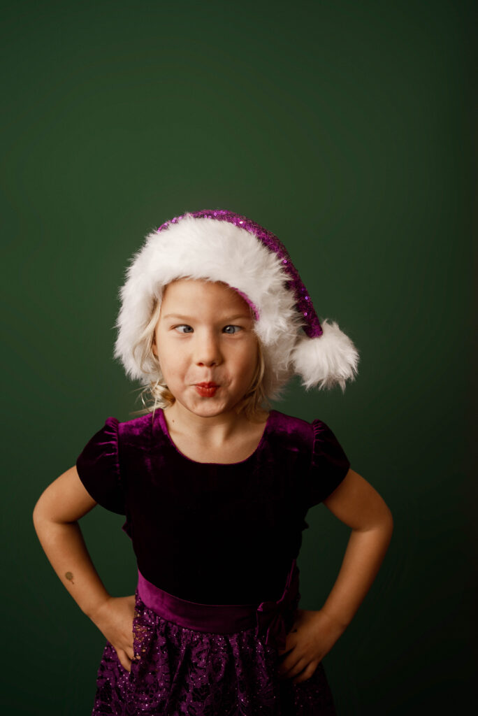 young girl in santa hat and purple dress for chrismas portraits 