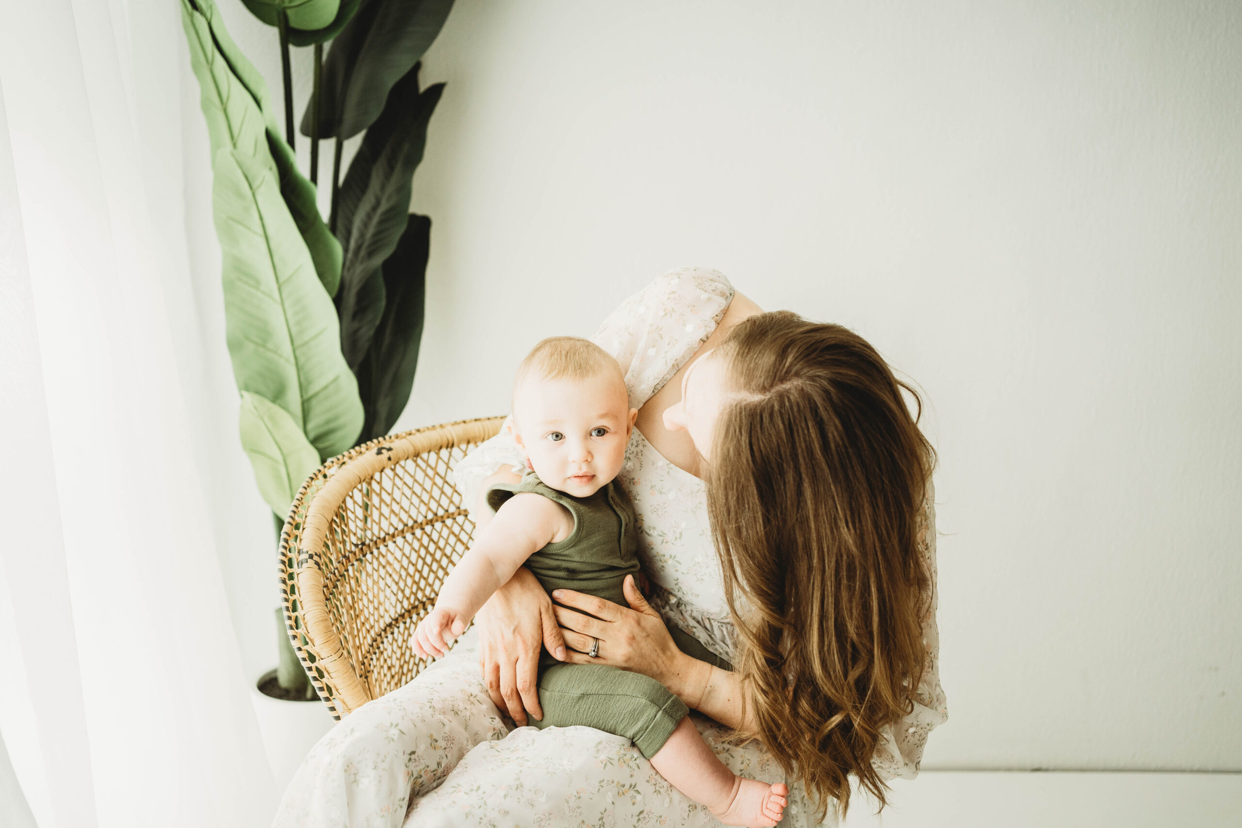 mother holding son in wicker chair.