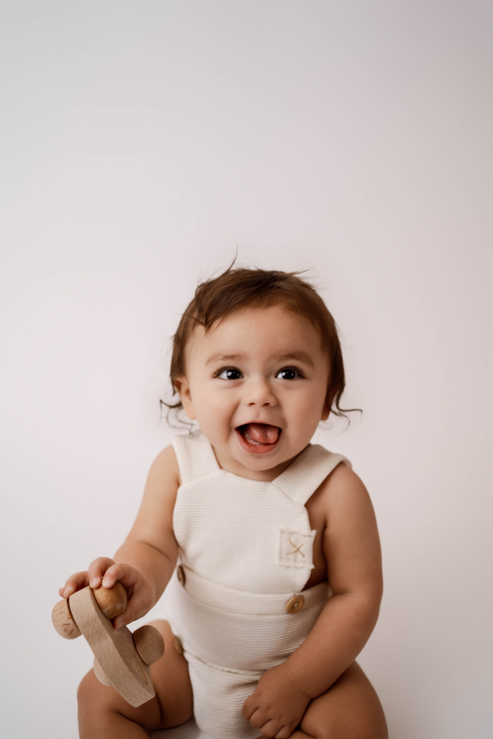 Baby in a white romper posing for their newborn sessions near Madison, WI.