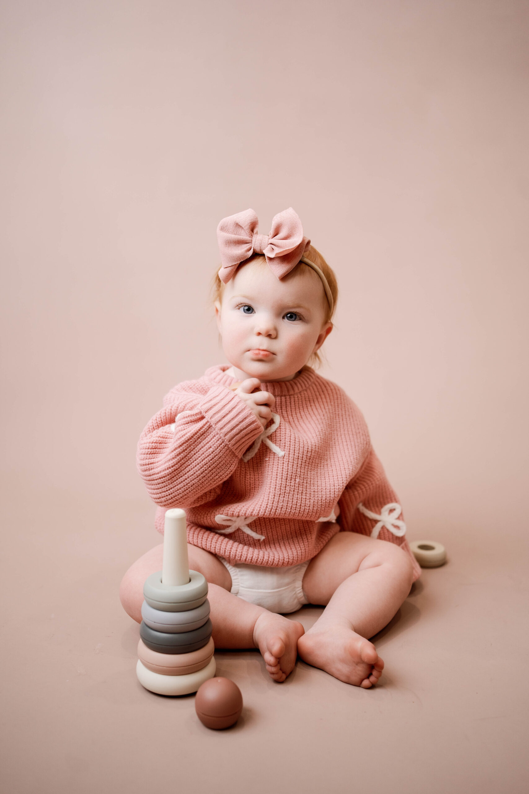 little girl wearing a pink sweater with white bows for her one year cake smash near sun prairie, wi
