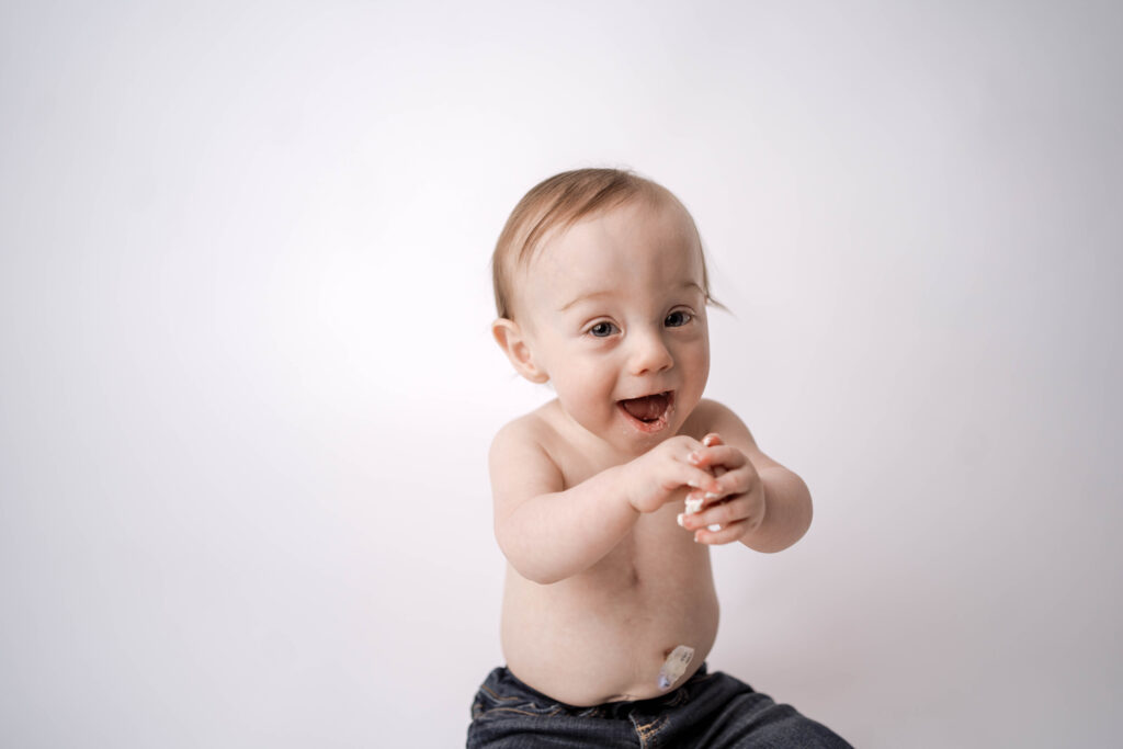one year old boy celebrating with a one year portraits + cake smash.