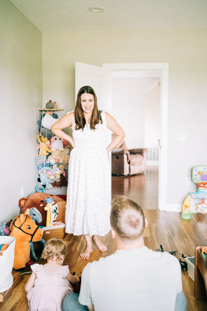 woman expecting baby and wearing a white floral dress in lifestyle maternity session