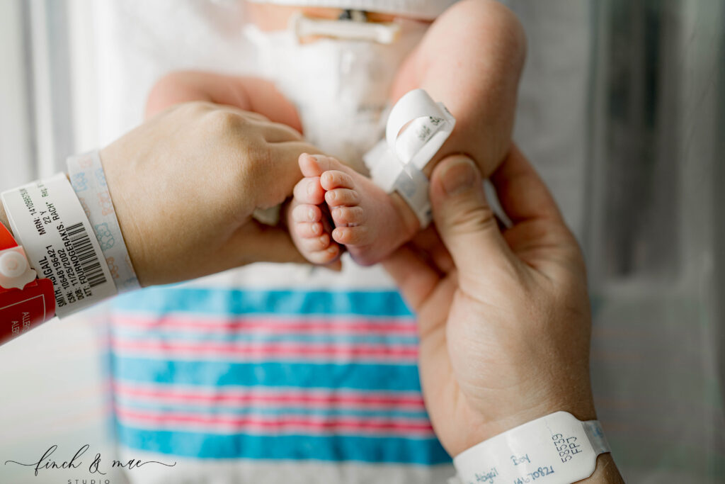 Tiny newborn feet held by parents during Fresh 48 hospital photography in Wisconsin.