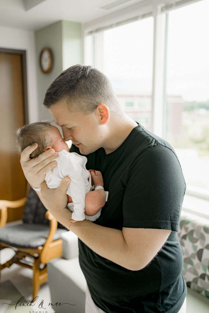 Father holding newborn baby close during Fresh 48 hospital photography session in Madison, Wisconsin.