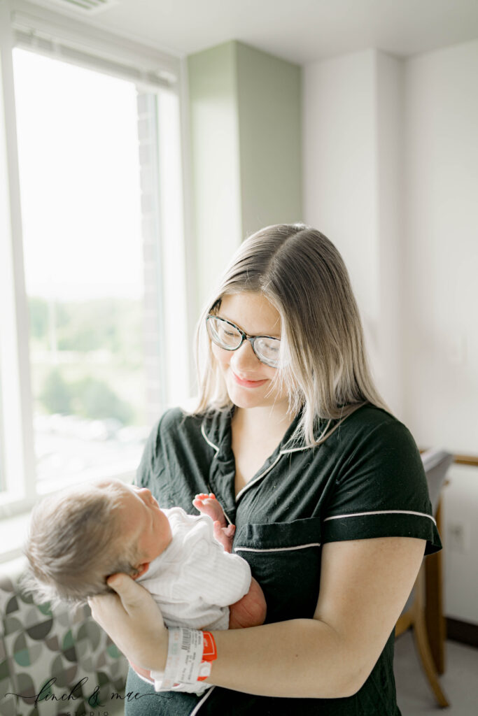Mother holding her newborn baby in hospital room with natural light, Fresh 48 photography Madison WI.