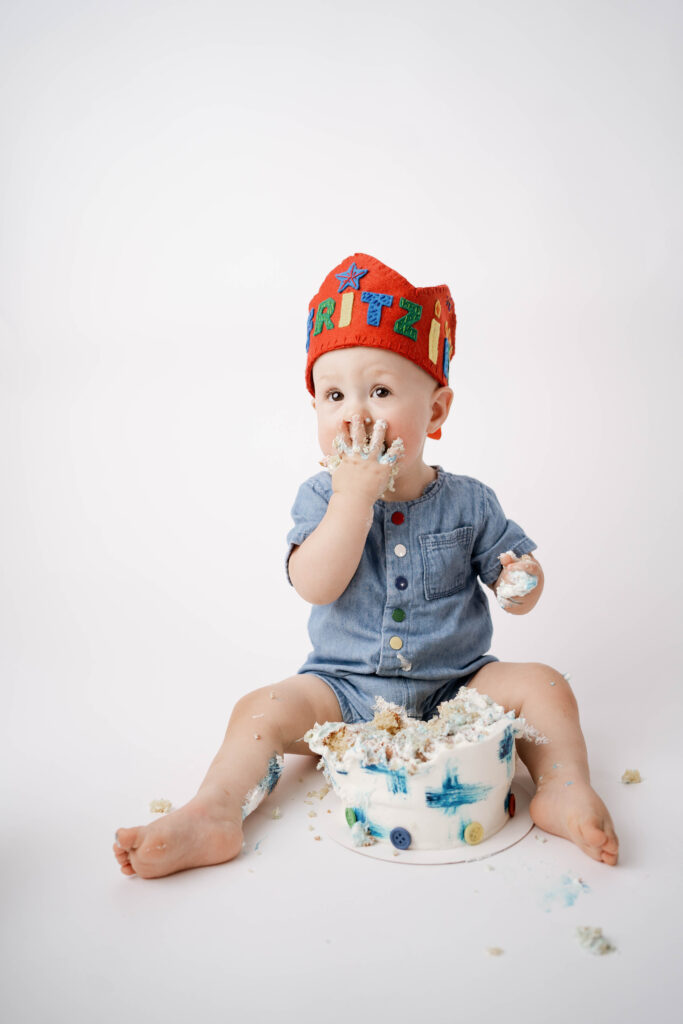 Stougton, WI Cake Smash Photography session of a boy in a blue romper with red crown.