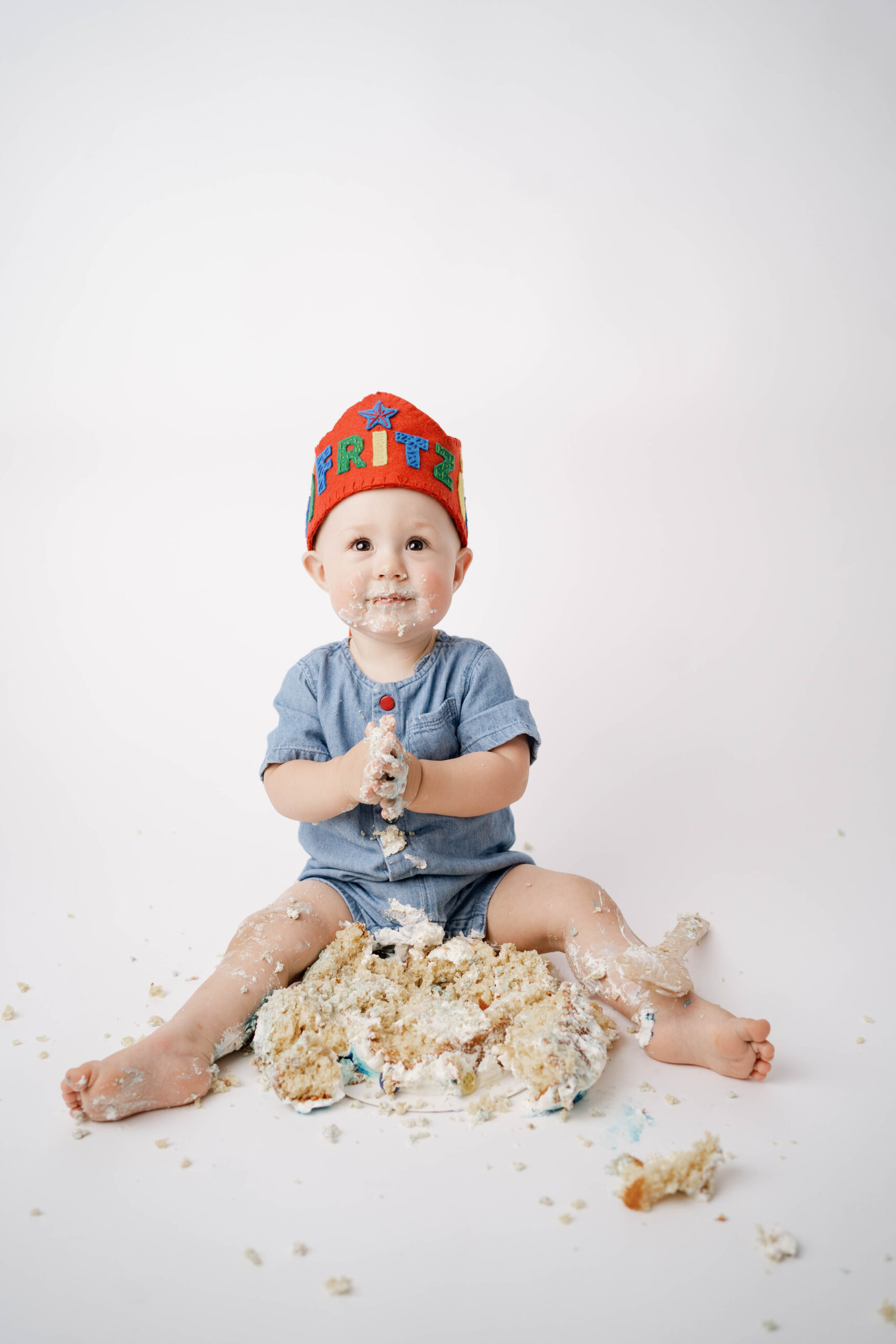 Cross Plains, WI Cake Smash Photography session of a boy in a blue romper with red crown.