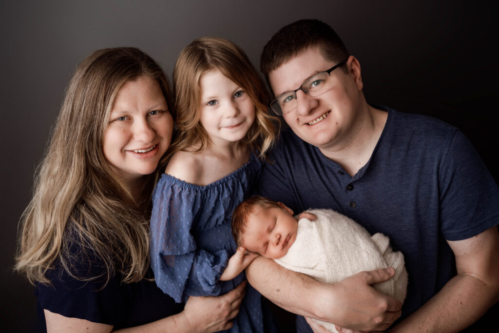 mom, dad, big sister and baby brother posing in the rio, wi studio for a newborn session
