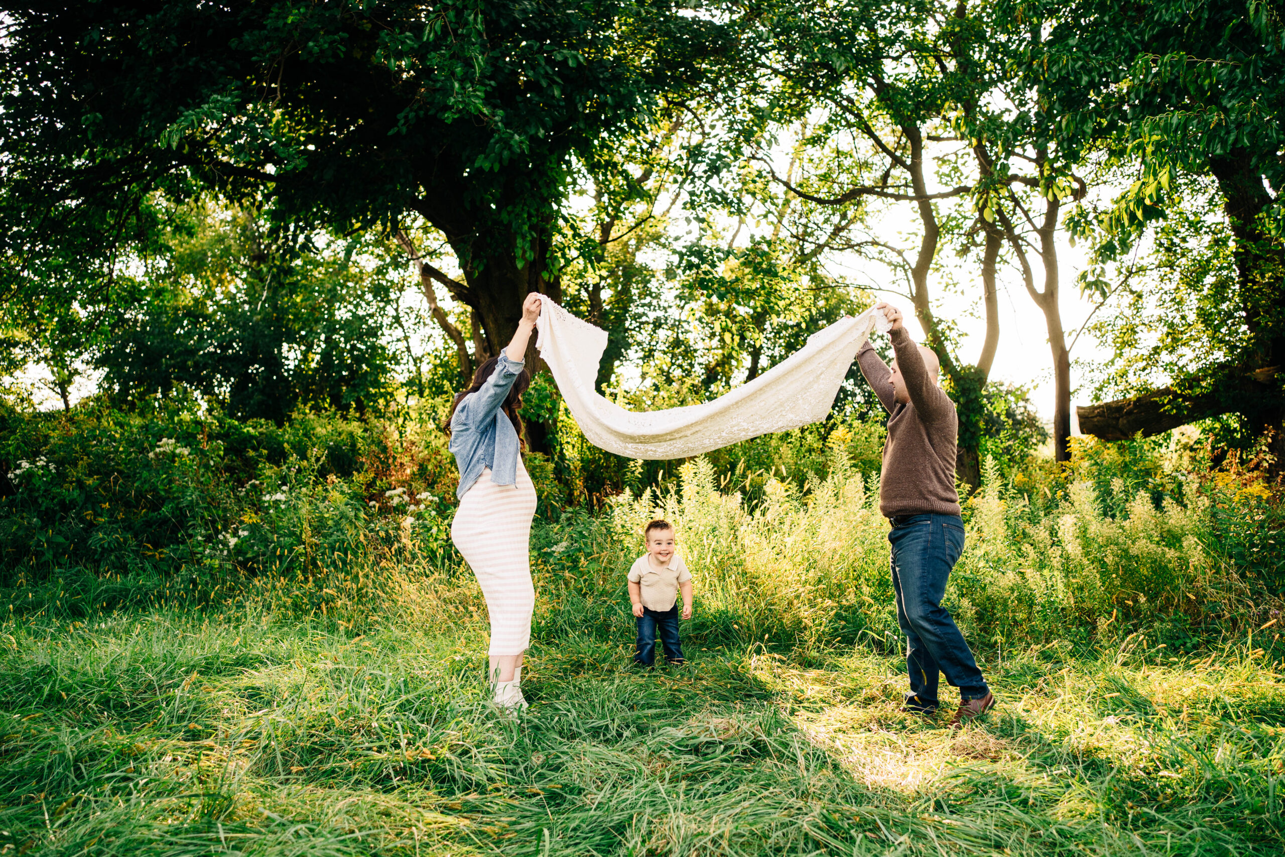 mom and dad playing a parachute game with their toddler.