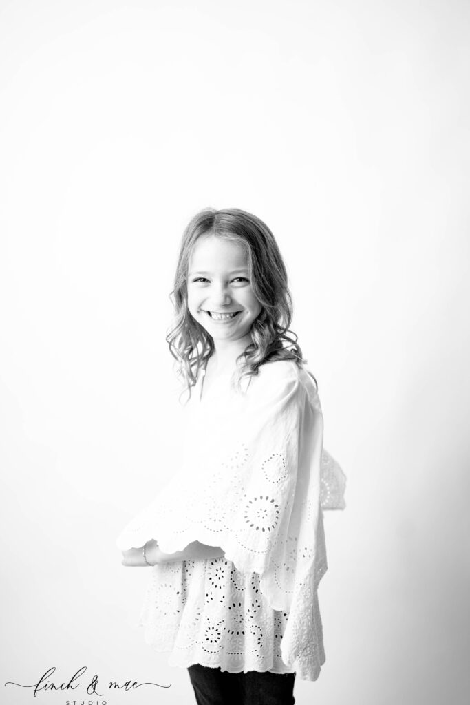 Side view of a laughing girl with curly hair, playful and heartfelt children’s studio photography in Rio WI.