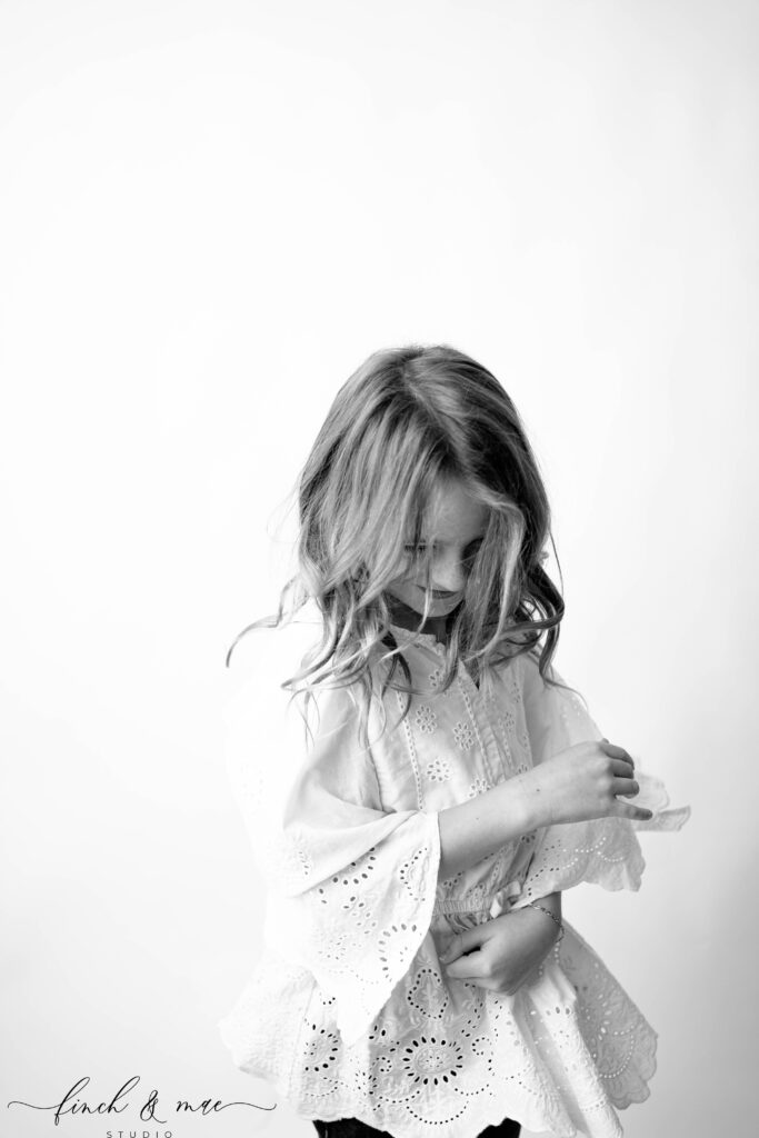 Quiet, thoughtful black and white moment of a girl looking down, emotive children’s fine art portrait session.