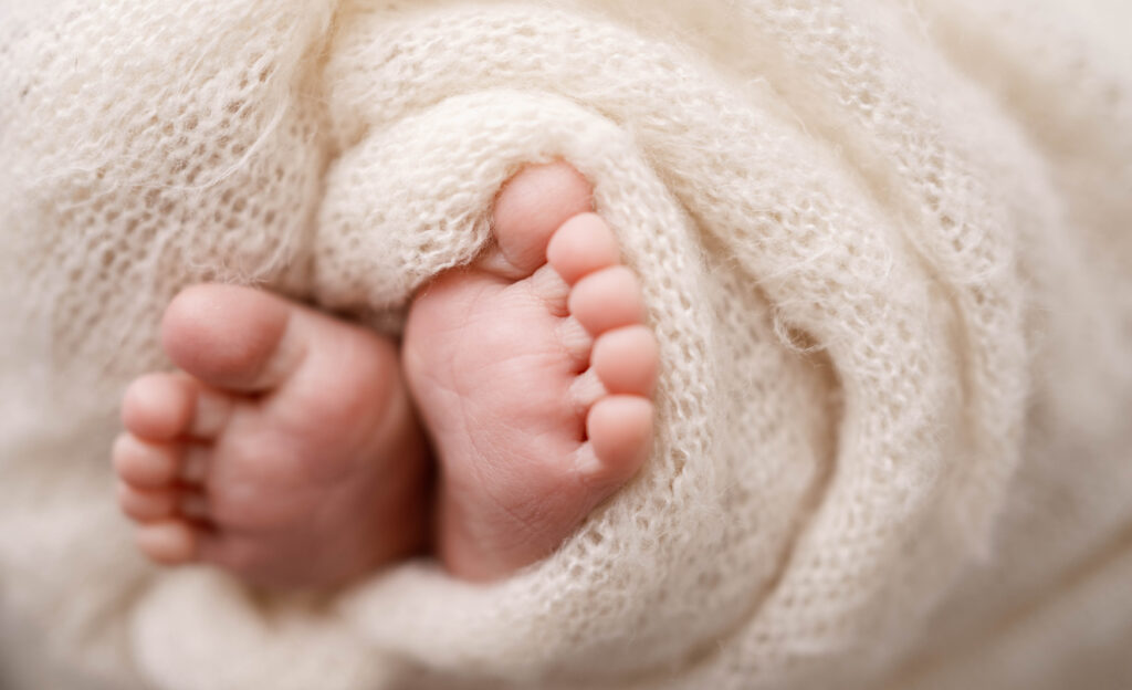 newborn feet wrapped in a cream wrap while getting photographed in a rio, wi studio