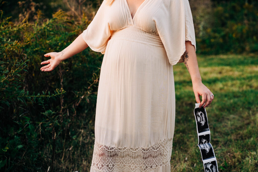 A woman is walking through a Wisconsin field of holding her ultrasound pictures and feeling the greeney