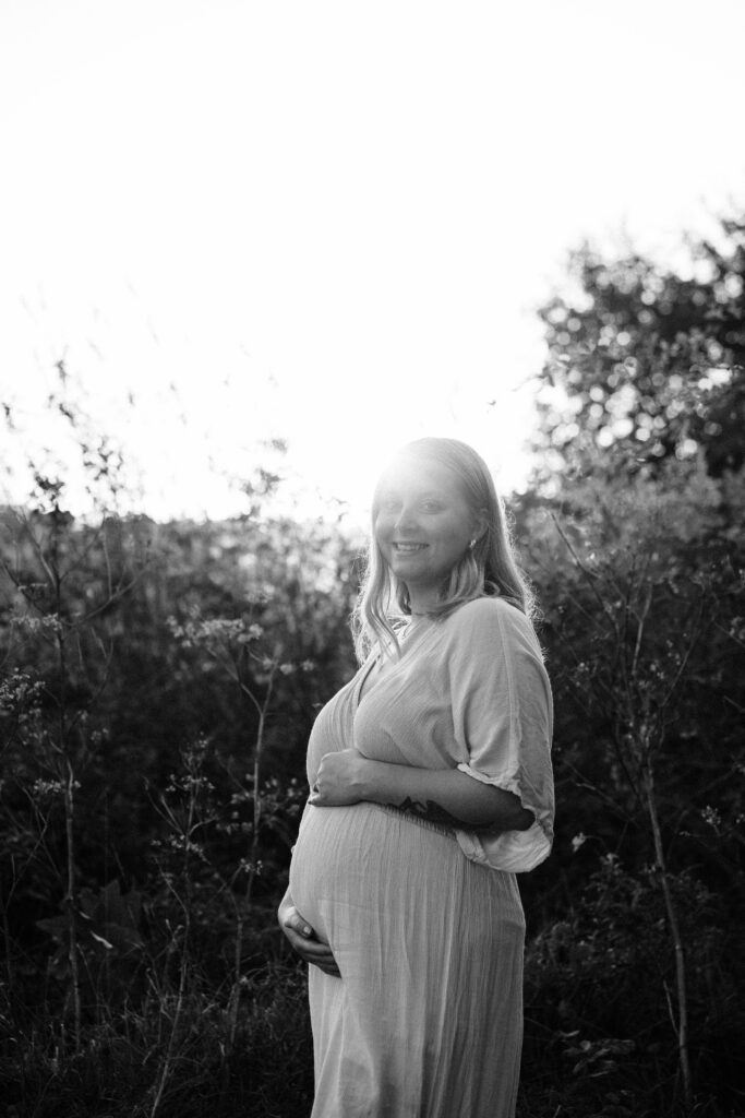 A mother is expecting and crossing her belly in this black-and-white photo