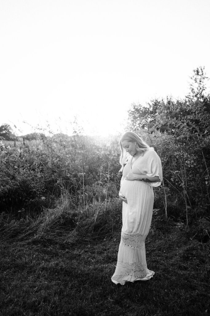 A black-and-white photo of an expecting mother caressing her belly
