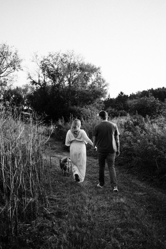 A black-and-white photo of a couple walking together with their dog in Wisconsin