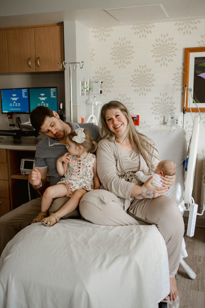 mom, dad, big sister and baby brother sitting on a hospital bed in a fresh 48 hospital session near milwaukee wi 