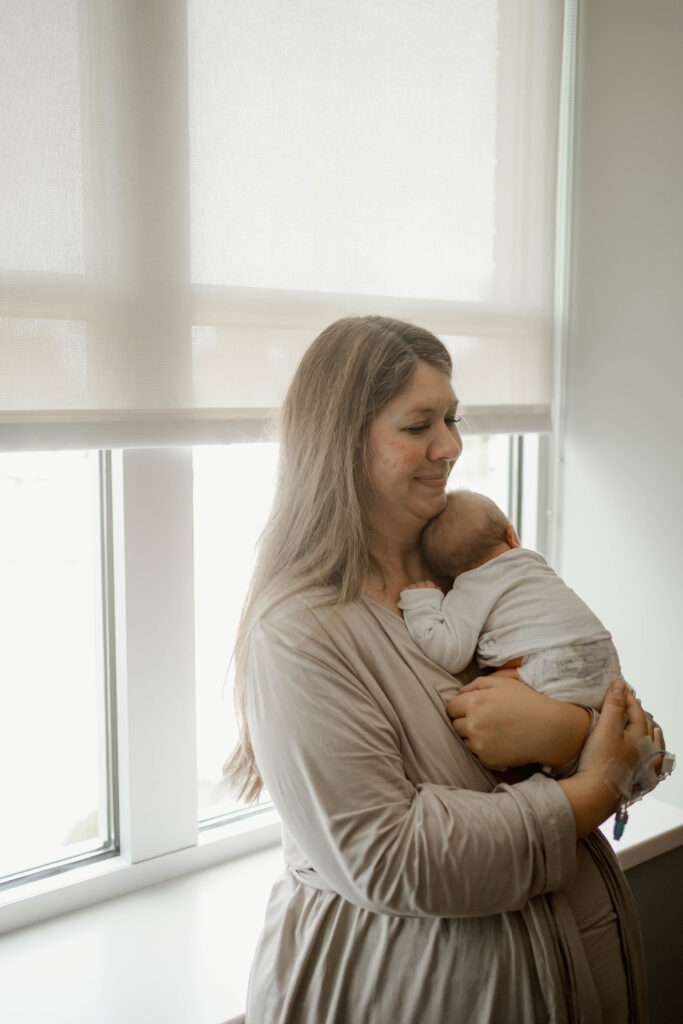 mom snuggling newborn baby at fresh 48 hospital session near milwaukee