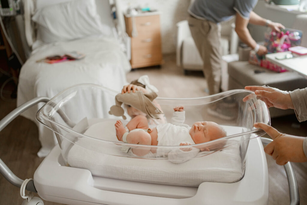 big sister giving baby brother a toy at fresh 48 hosptial session near milwaukee wi