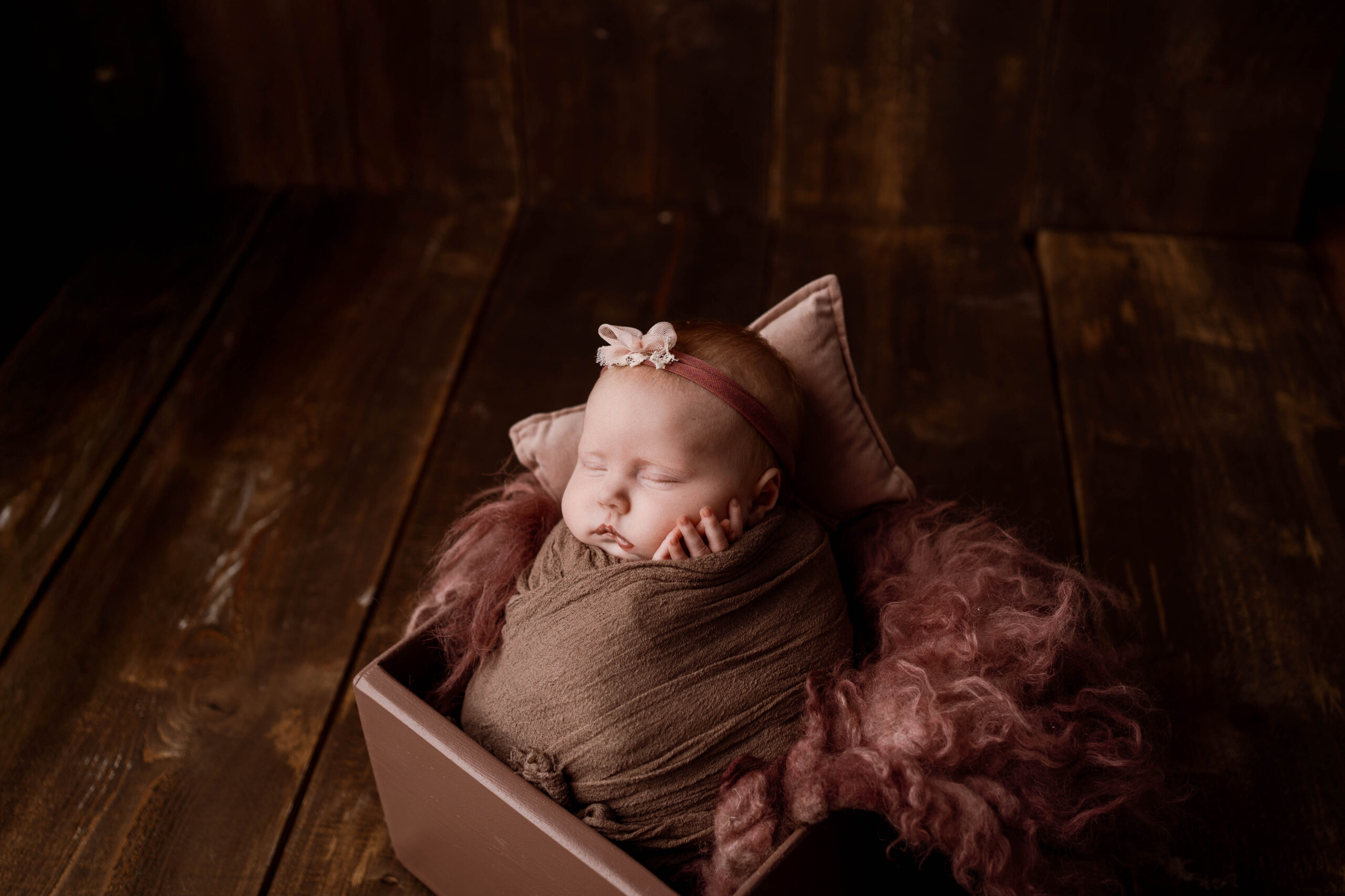 newborn girl in a purple box with a purple wrap for her newborn session near madison wi