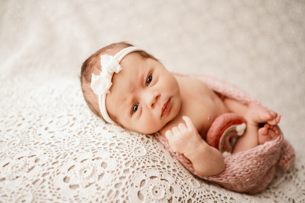 Newborn baby girl, looking at the camera, laying on a crocheted blanket in Rio, Wisconsin newborn Studio