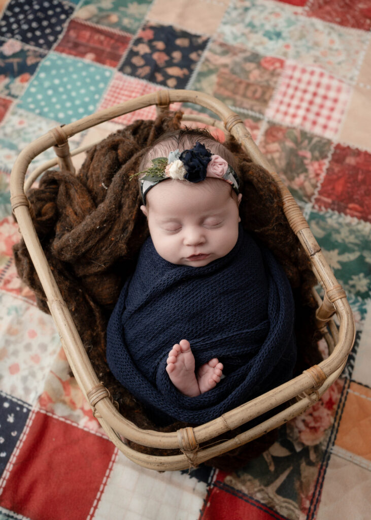 baby in vintage basket with rich layered textiles newborn photography in rio Wisconsin 
