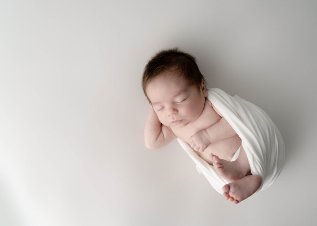 sleeping newborn baby boy wrapped in a white wrap in rio, wi newborn studio