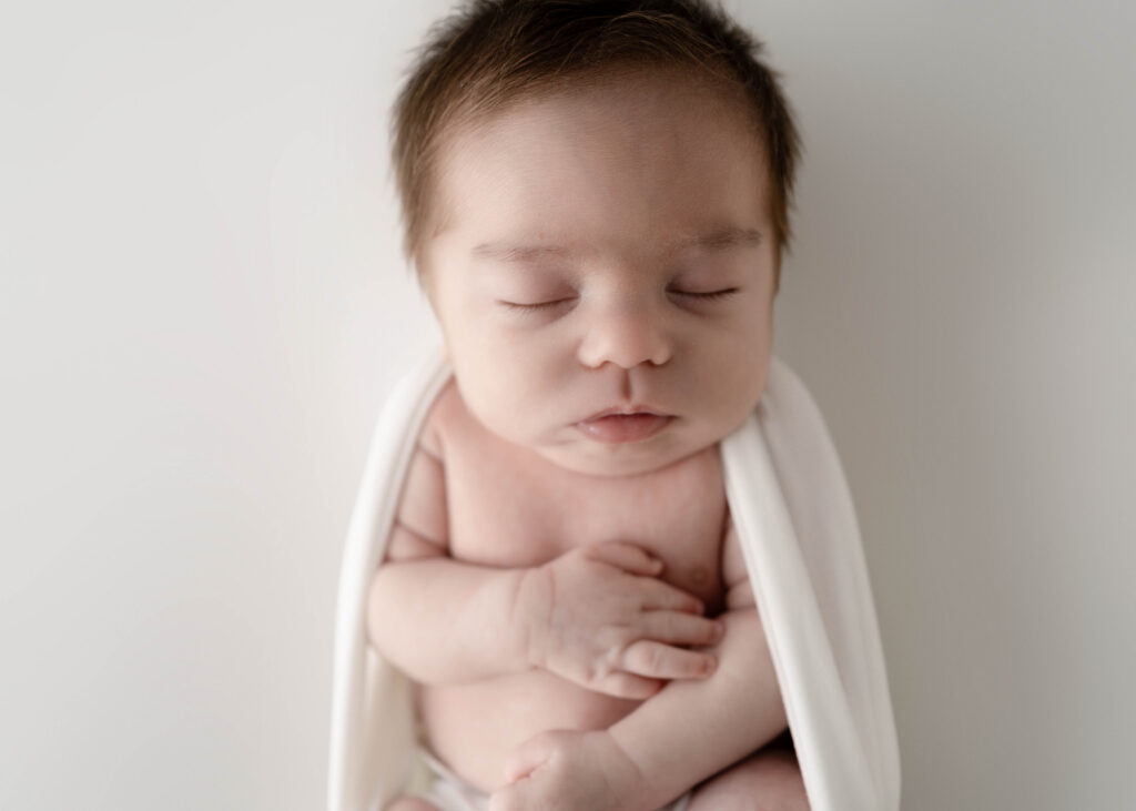 newborn boy wrapped in a white wrap