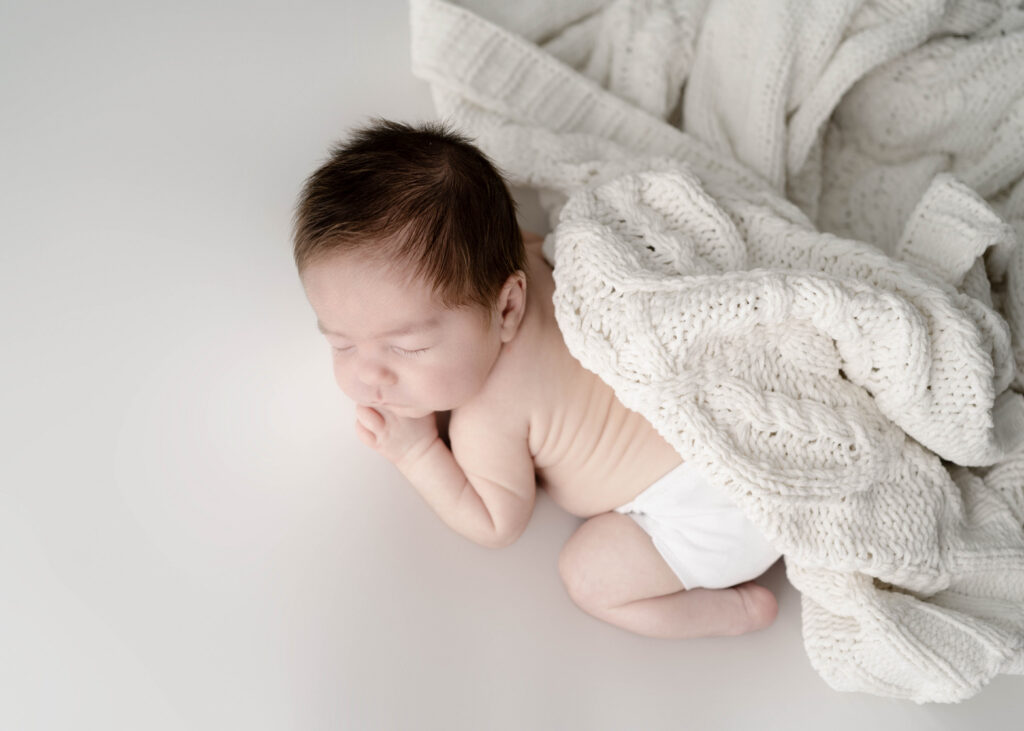 sleeping newborn baby with a knitted white blanket