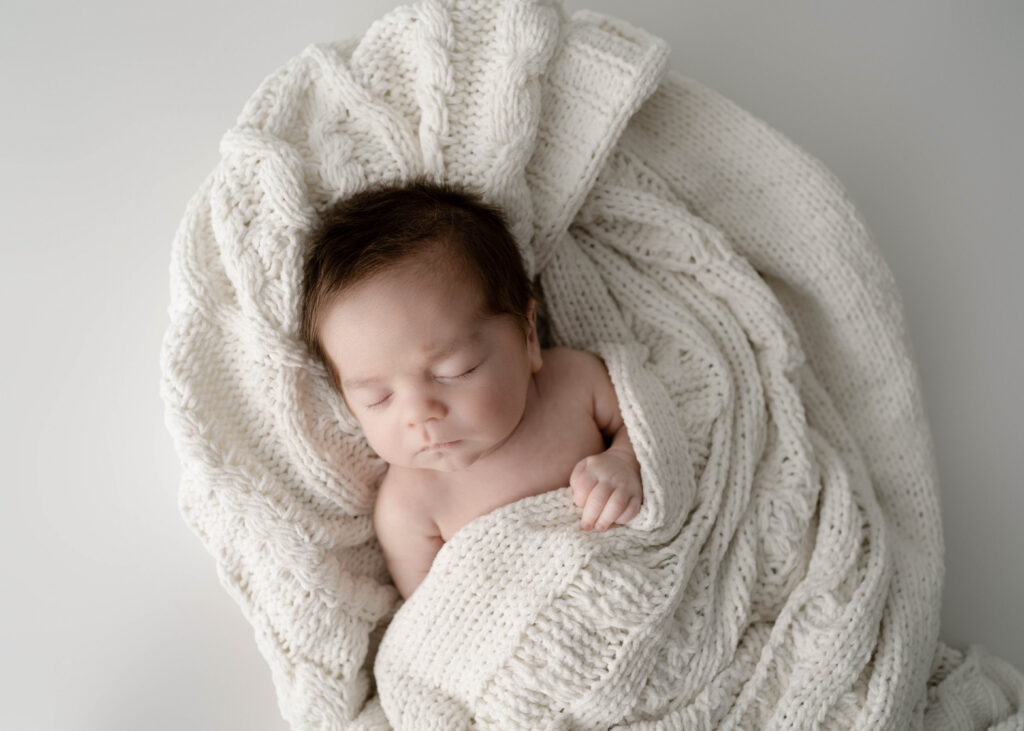 sleeping boy wrapped in a knitted white blanket