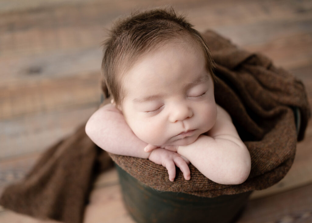 green metal bucket with a sleeping baby boy
