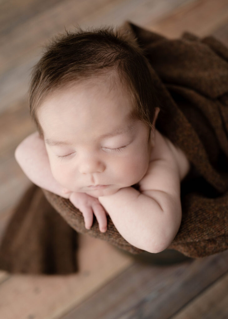newborn boy in a prop bucket