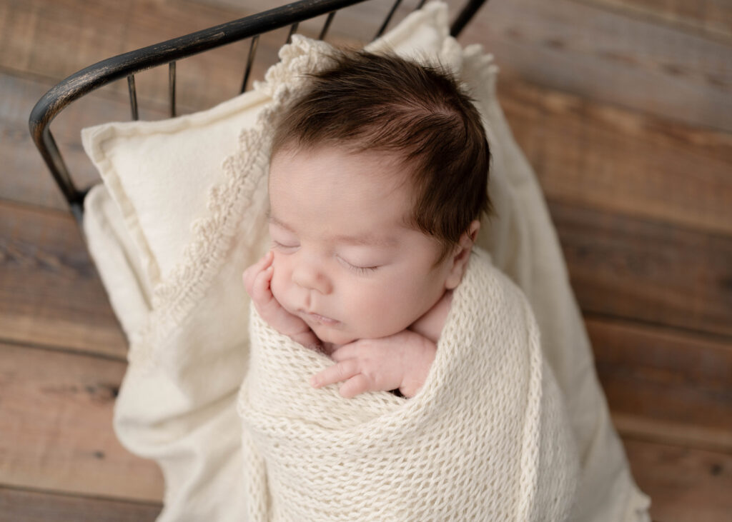 sleeping newborn baby on a metal bed