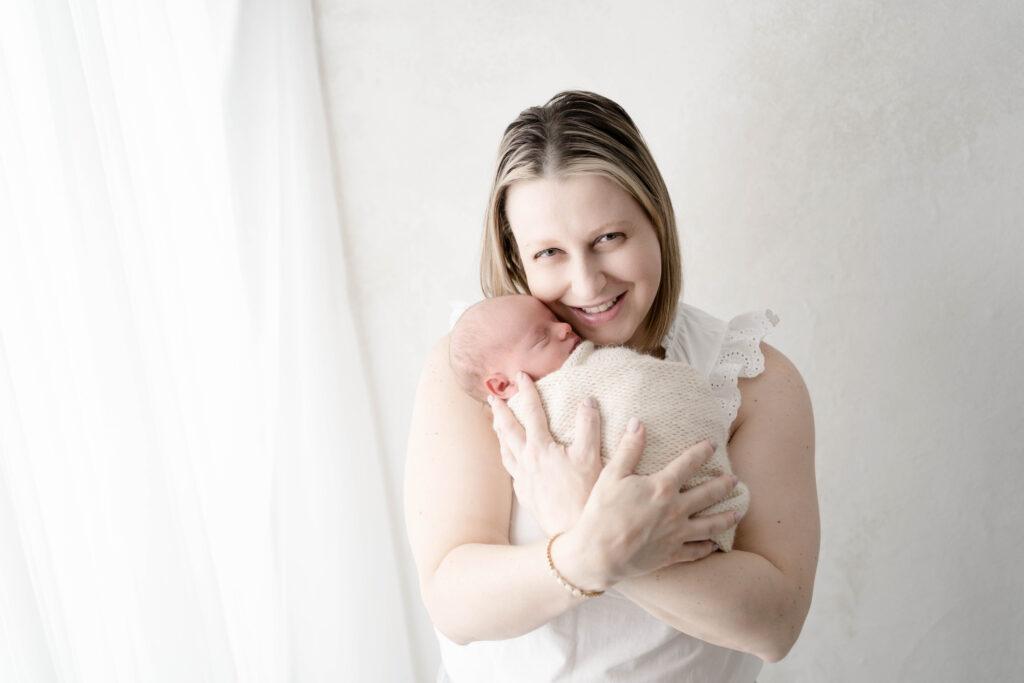 New mother holding her newborn baby during a studio newborn photography session at Finch & Mae Studio.