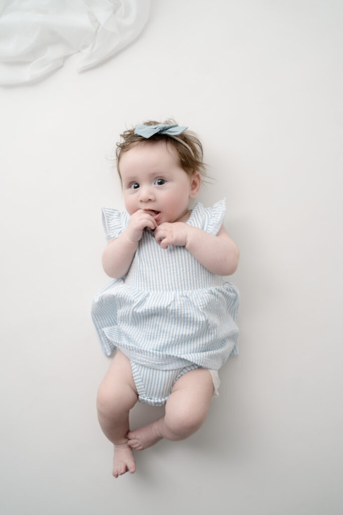 Six-month milestone portrait of baby girl lying on a neutral backdrop at Finch & Mae Studio in Rio, Wisconsin.
