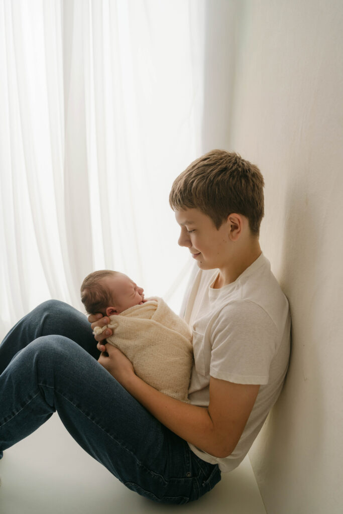 Big brother snuggling newborn brother in Rio WI newborn portrait studio