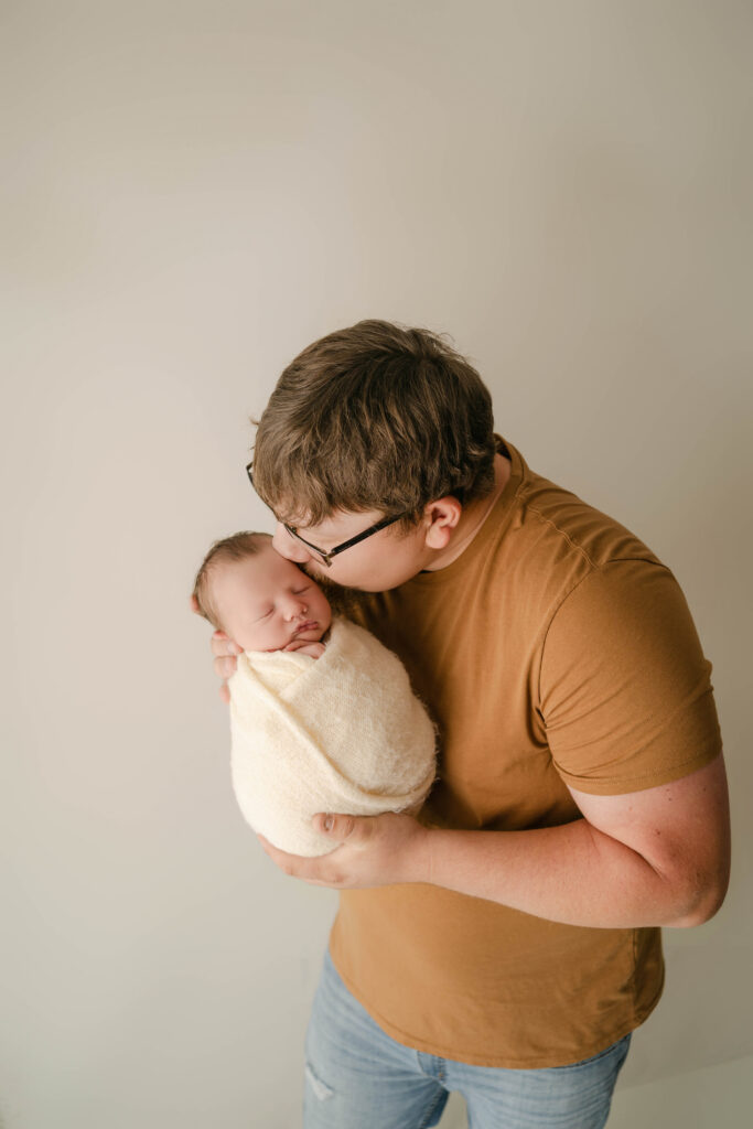 Dad is kissing newborn son's temple in Rio, WI newborn studio