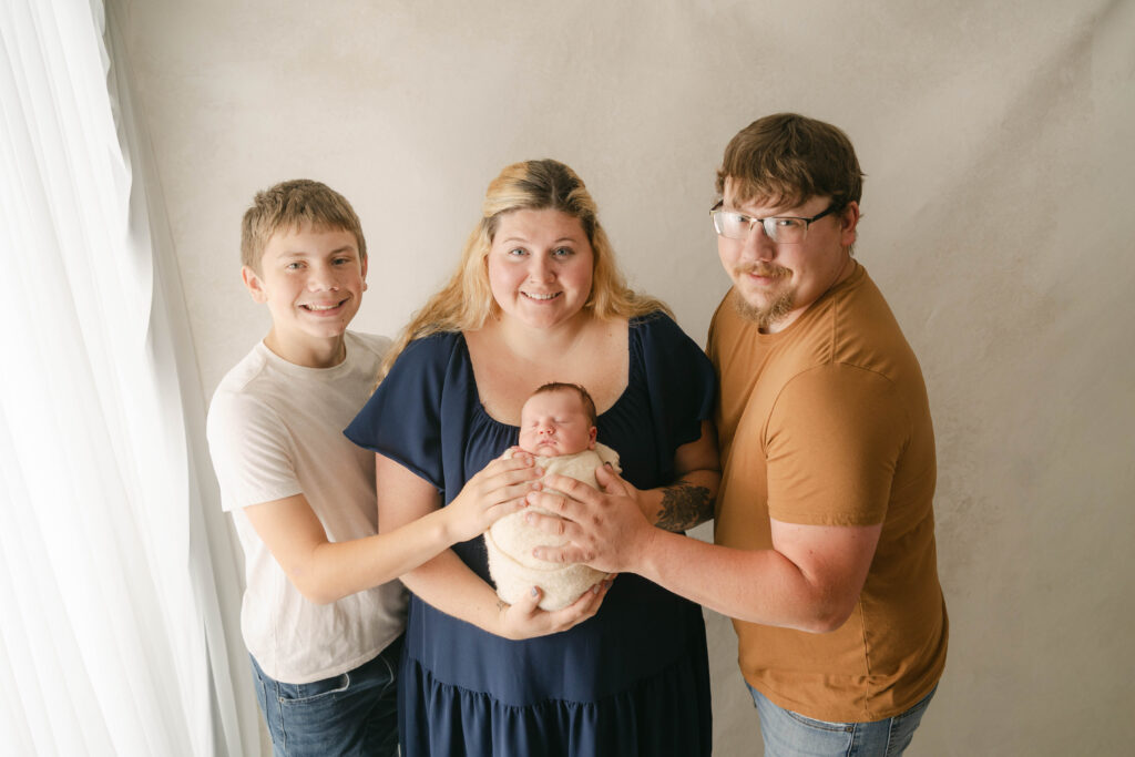 parents plus older brother are holding newborn baby in Rio, WI newborn portrait studio