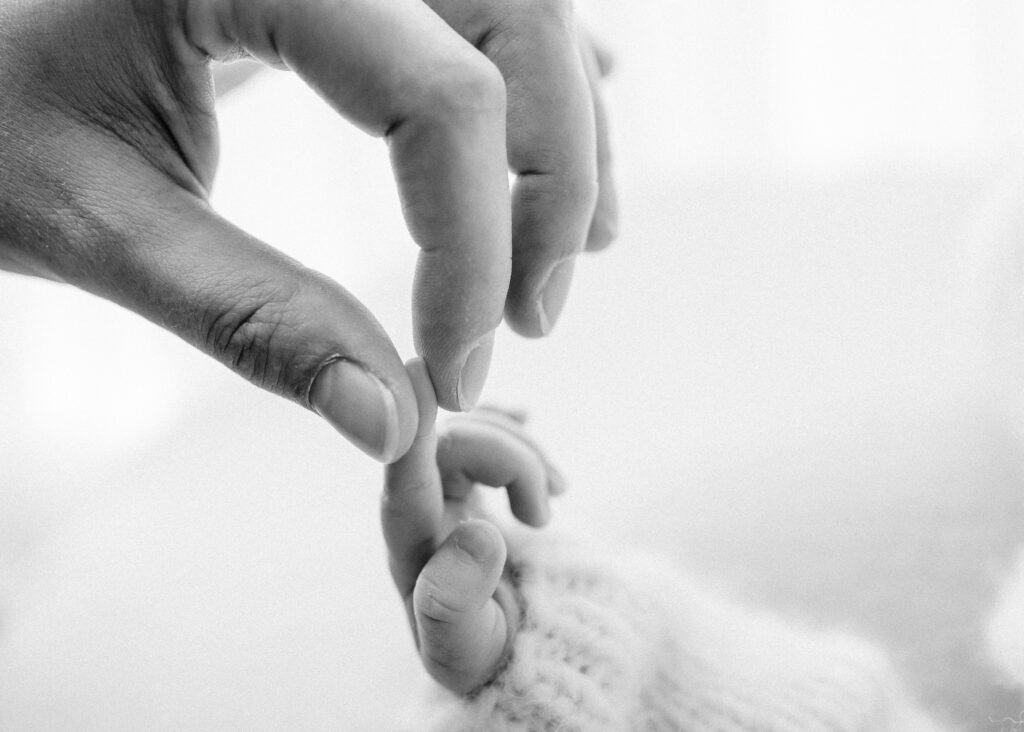 Mom's hand holding newborn baby's finger