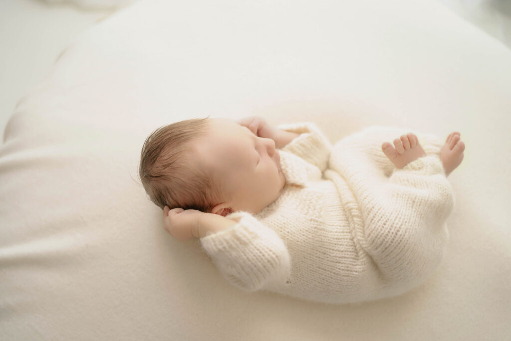 newborn boy wearing a soft white outfit for newborn portraits near waunakee wi