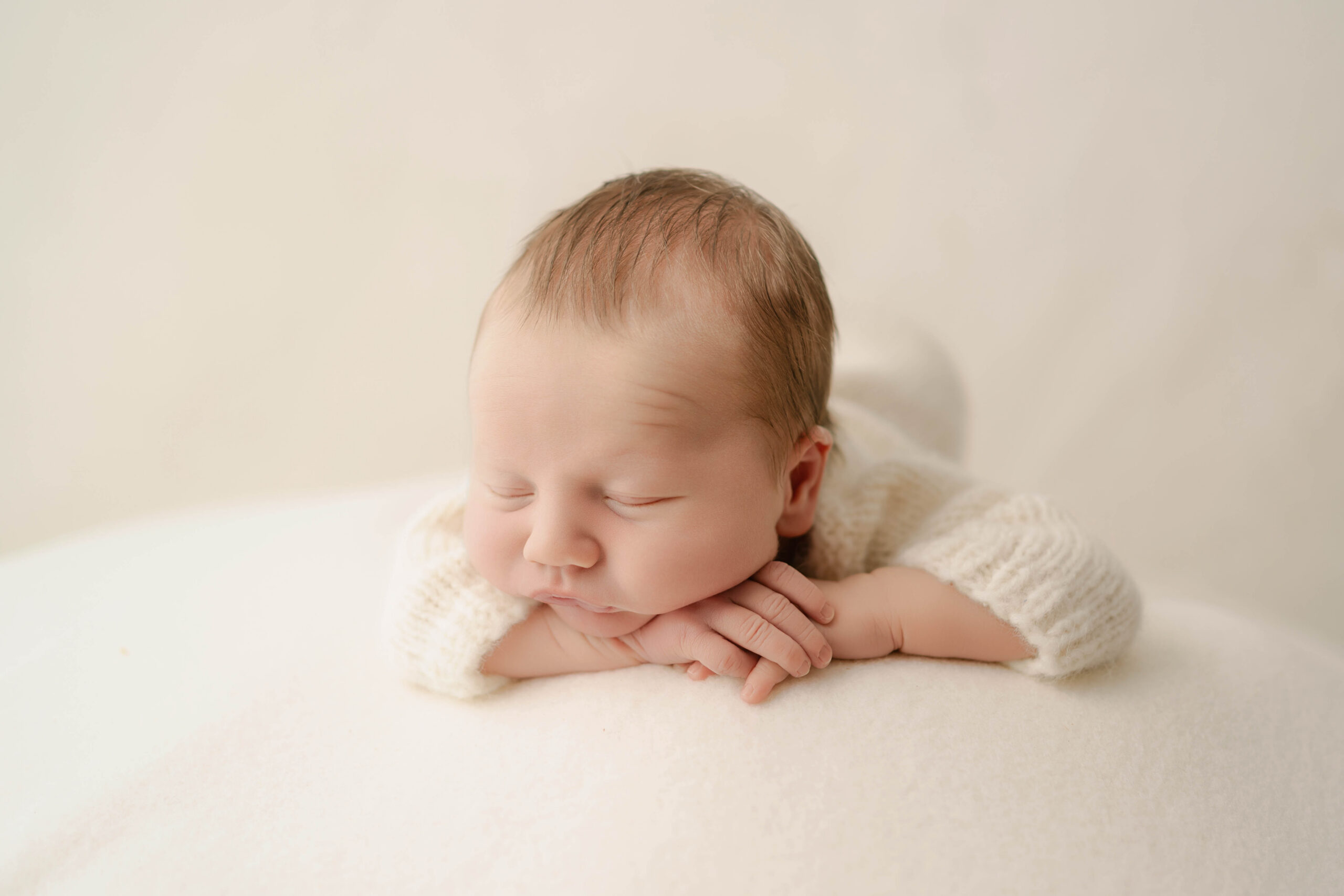 newborn boy sleeping on a white blanket