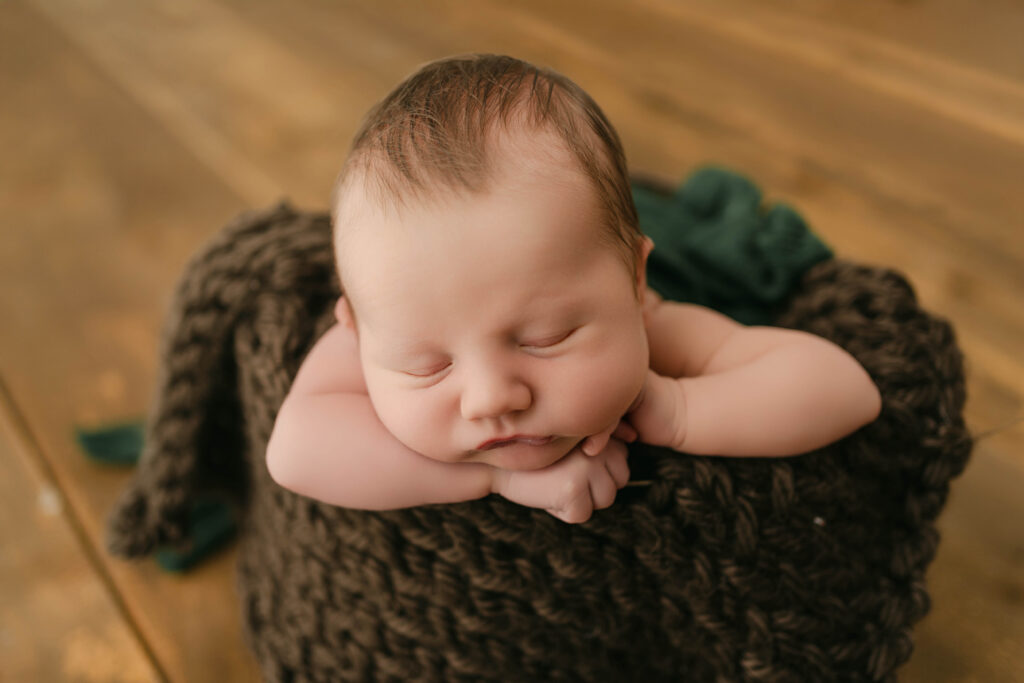 newborn boy is posed in a bucket near sun prairie wi