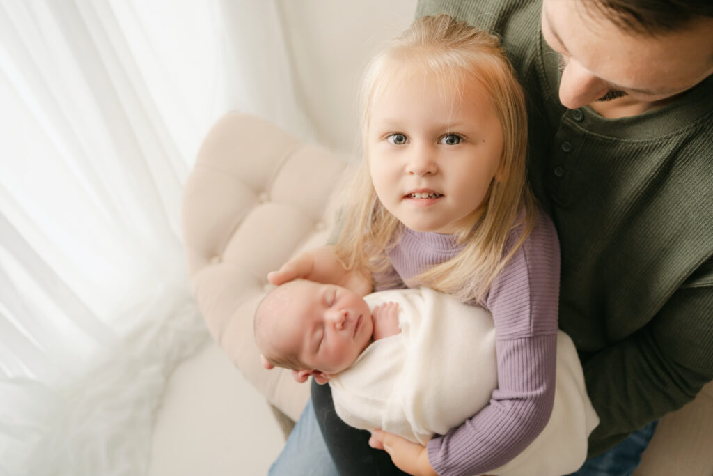 Dad helping big sister holding baby brother -Newborn photography session near Madison, WI