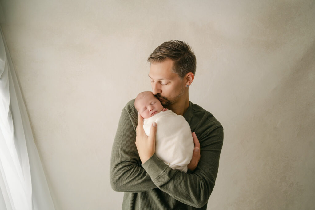 Dad kissing newborn son's temple - Newborn photography session near Madison, WI
