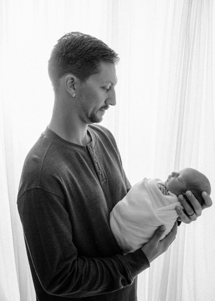 Backlit image of dad holding newborn son - Newborn photography session near Madison, WI