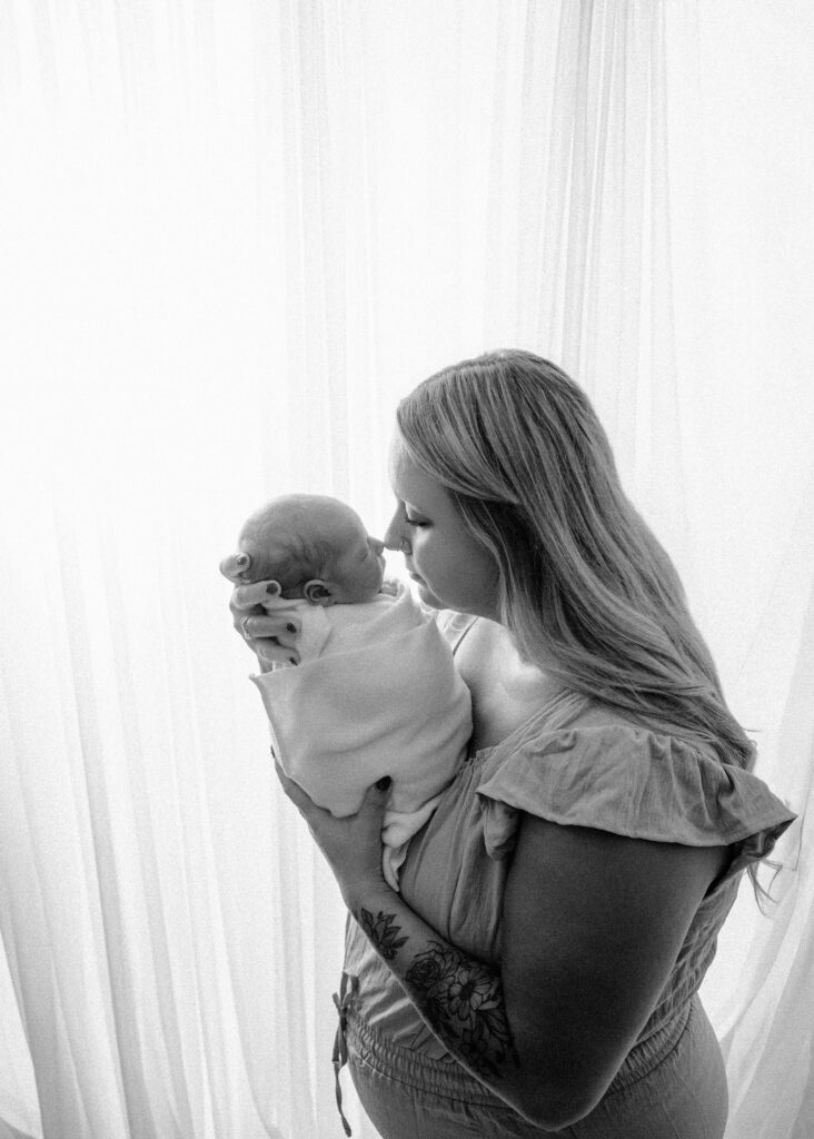 Backlit image of mom holding son to her nose - Newborn photography session near Madison, WI