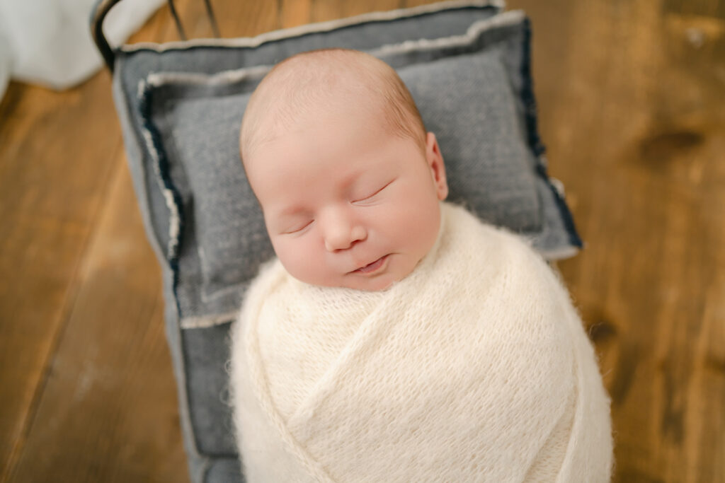 newborn in a white wrap sleeping on a bed - Newborn photography session near Madison, WI